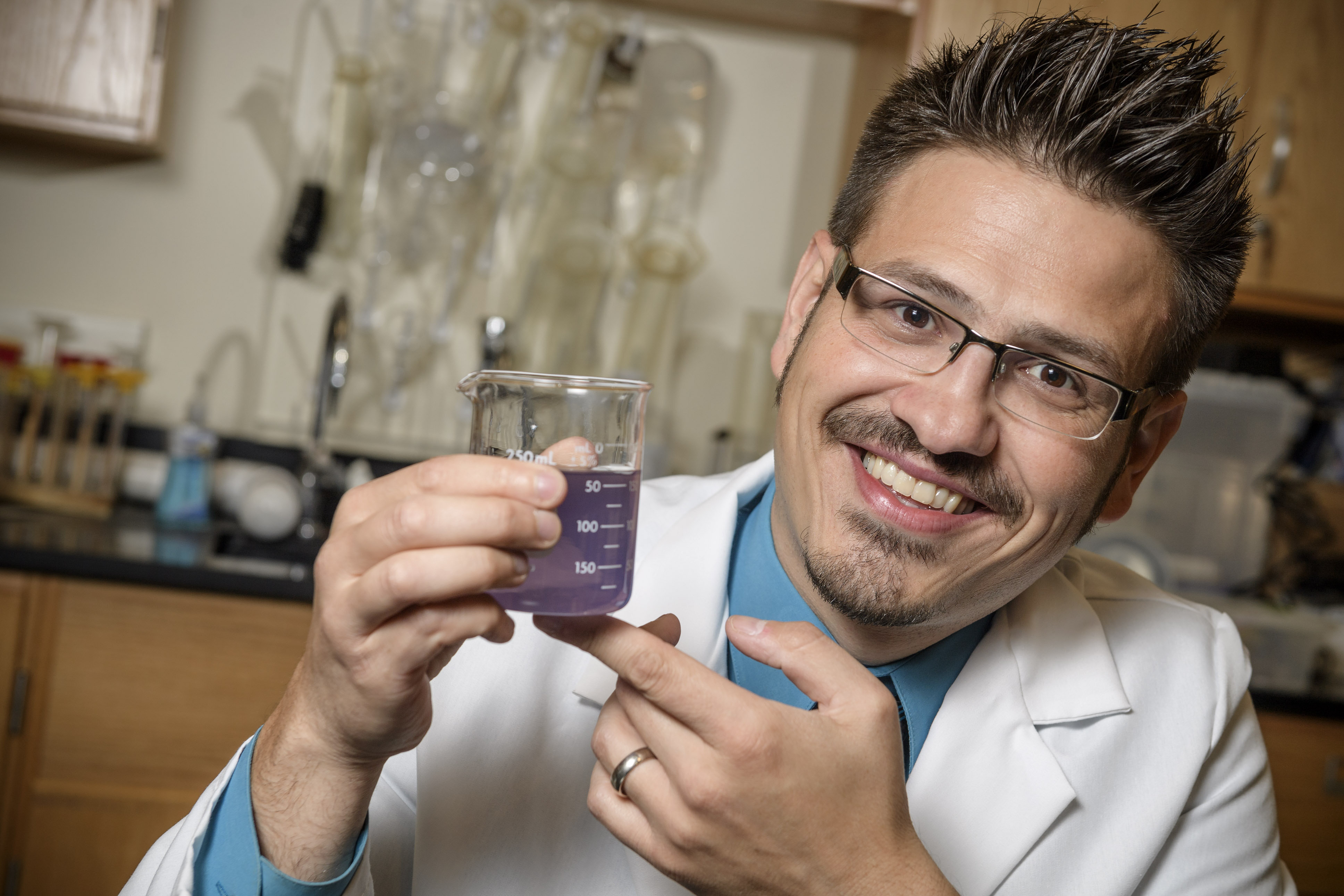 Mister C holding a beaker with fluid in it.